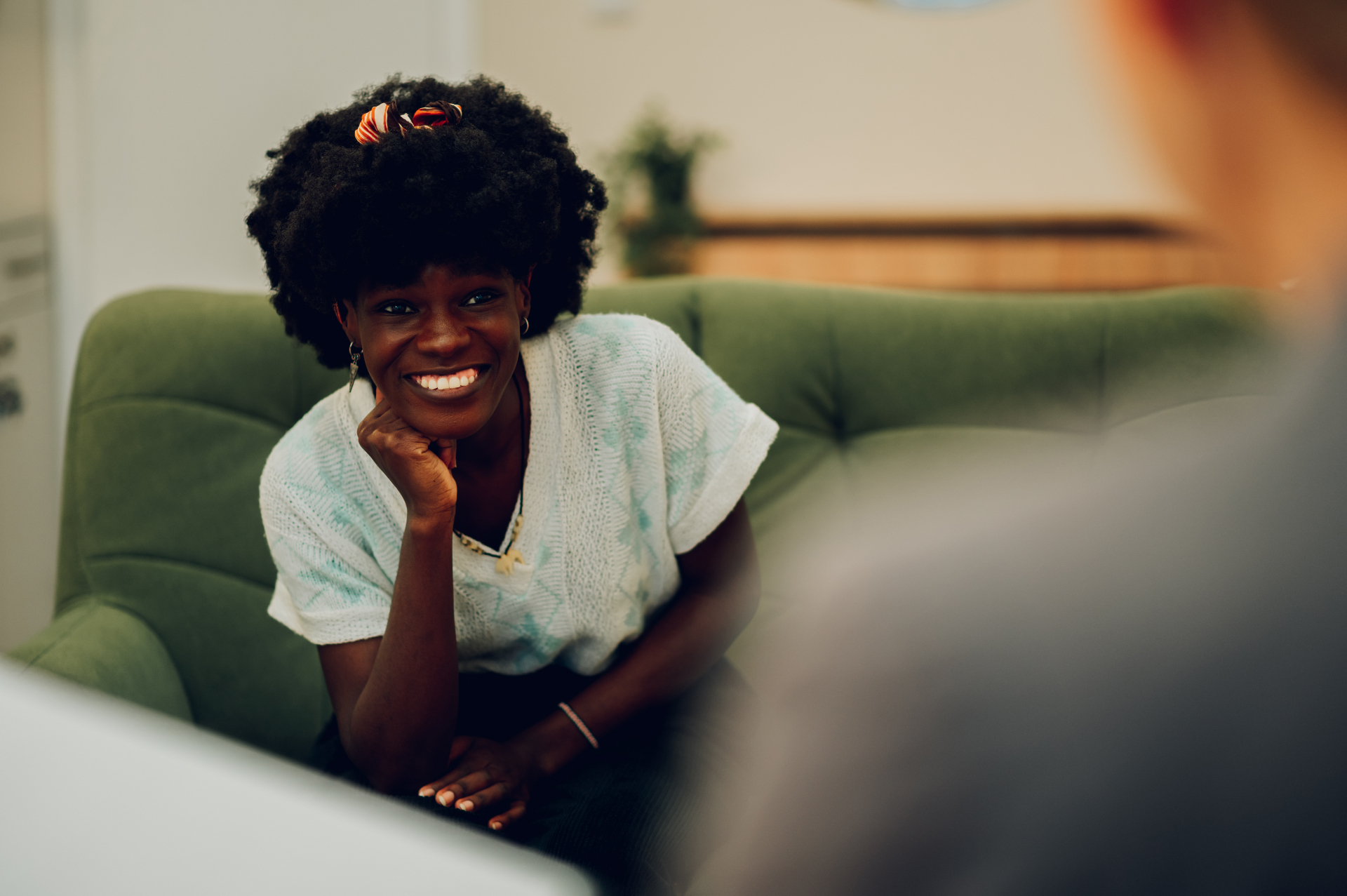 A client smiling warmly during a relaxed telehealth session from her living room couch