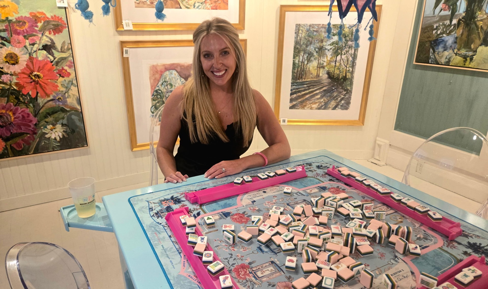 Jenelle smiling at a mahjong table set with tiles during a Mississippi mahjong event