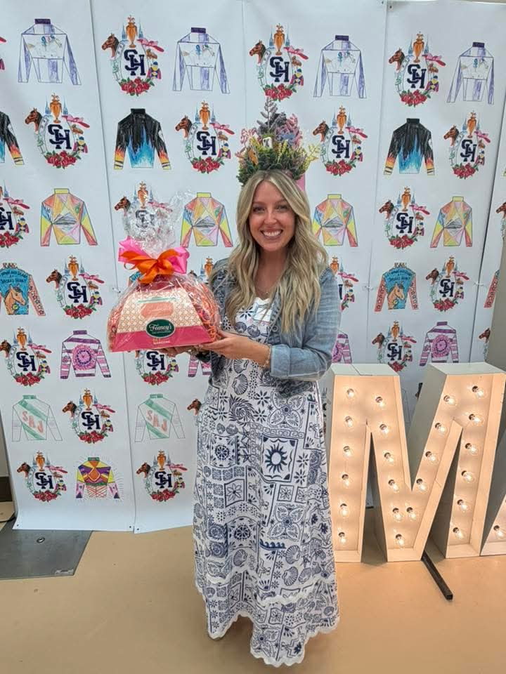 Jenelle at a Derby-themed mahjong celebration, holding a prize gift basket